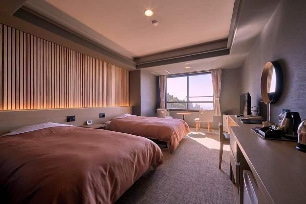 Habitación de hotel con dos camas, un escritorio, una silla, un televisor y una ventana con vistas.