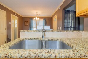 A kitchen with granite countertops, a double sink, and a chandelier. - Creekside Stay Near Fort Benning Sleeps 12! (Columbus)