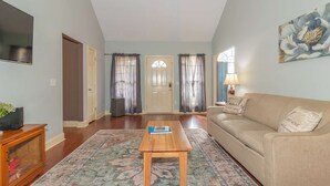 A living room with a wooden coffee table, beige sofa, and a patterned rug. - Creekside Stay Near Fort Benning Sleeps 12! (Columbus)
