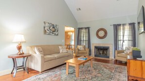 A living room with a sofa, armchair, coffee table, rug, fireplace, and a lamp. - Creekside Stay Near Fort Benning Sleeps 12! (Columbus)
