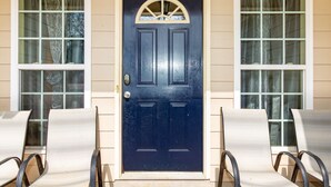 A dark blue front door with a small window above it, flanked by two windows with curtains. - Creekside Stay Near Fort Benning Sleeps 12! (Columbus)