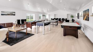 Une pièce spacieuse équipée d’une table de billard, d’un baby-foot et d’une table de ping-pong.