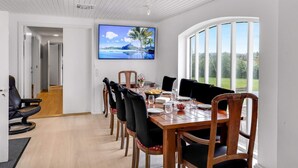 Un coin repas avec une table en bois, des chaises et un téléviseur fixé au mur qui diffuse une image panoramique.