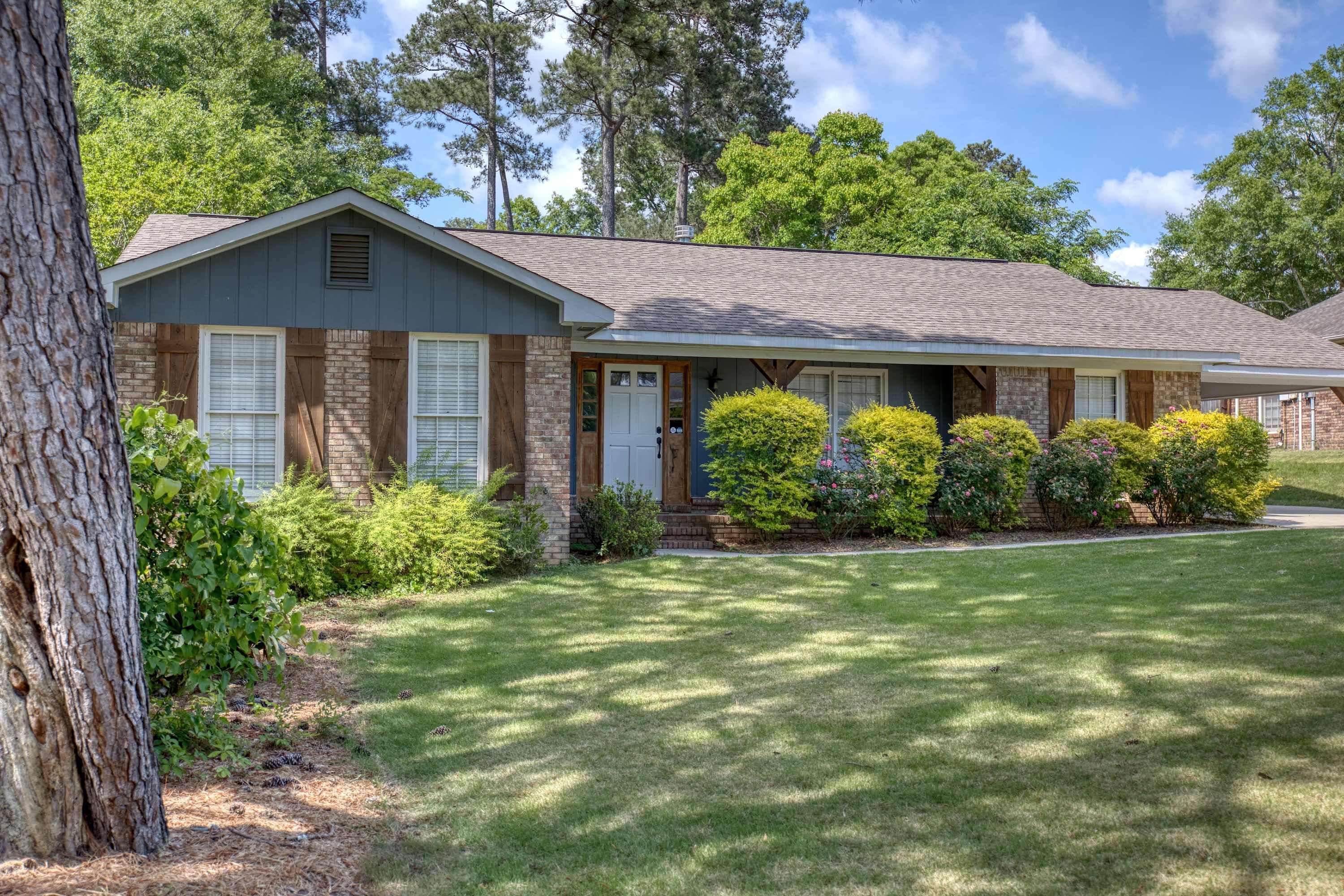 A two-story house with a front porch, brick exterior, and a well-maintained lawn.