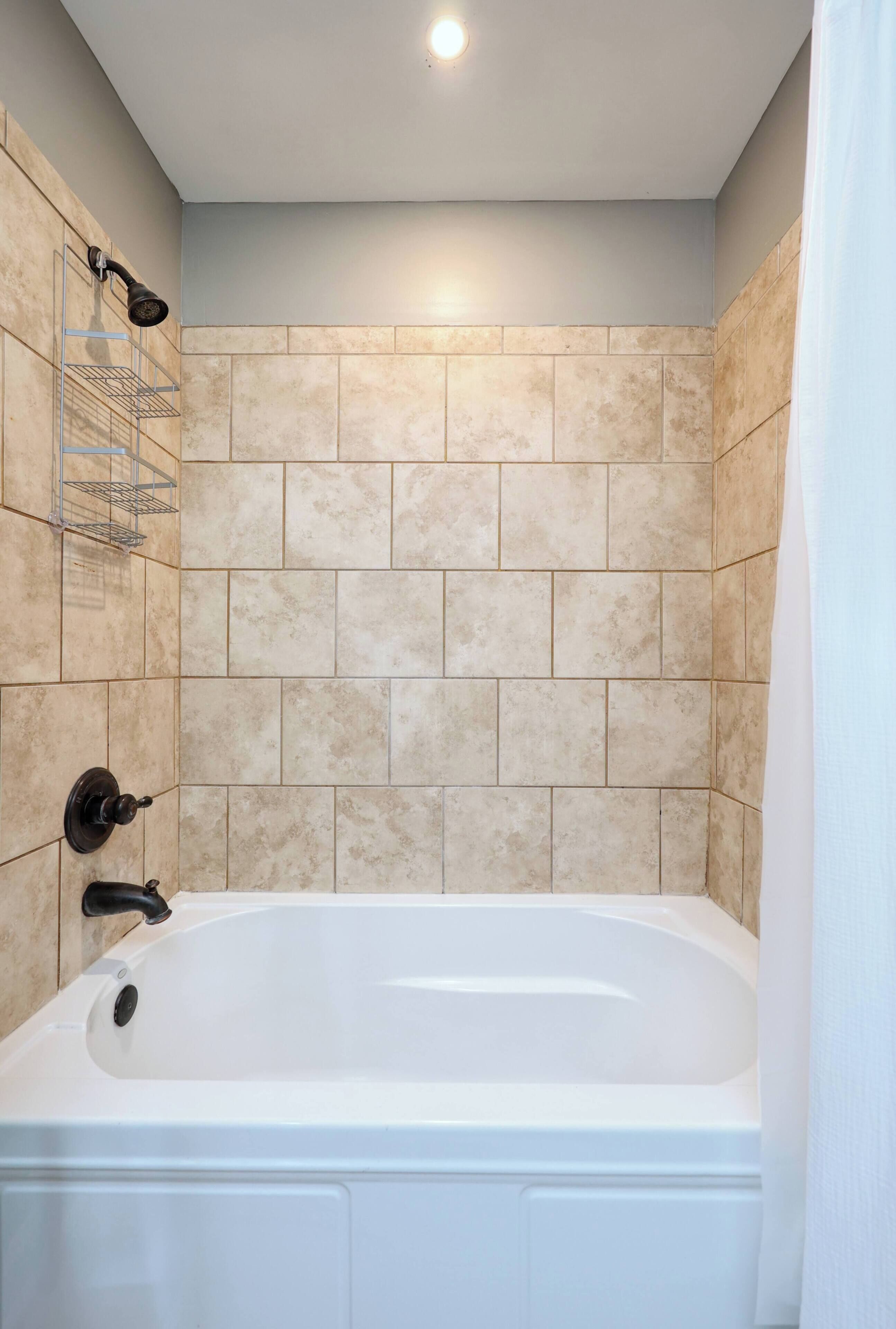 A bathroom with a bathtub, a shower head, and a towel rack.