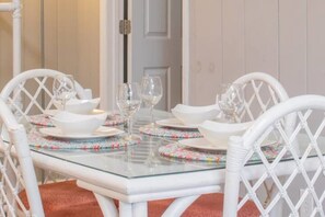 Ein Esstisch mit weißen Stühlen, einer Glasplatte und floralen Platzsets.