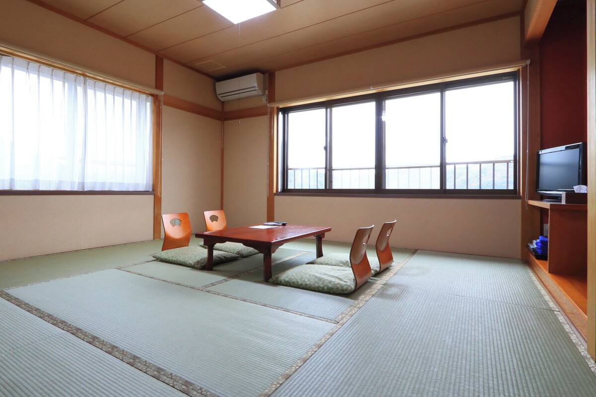 A traditional Japanese room with tatami flooring, a low table, and sliding doors.