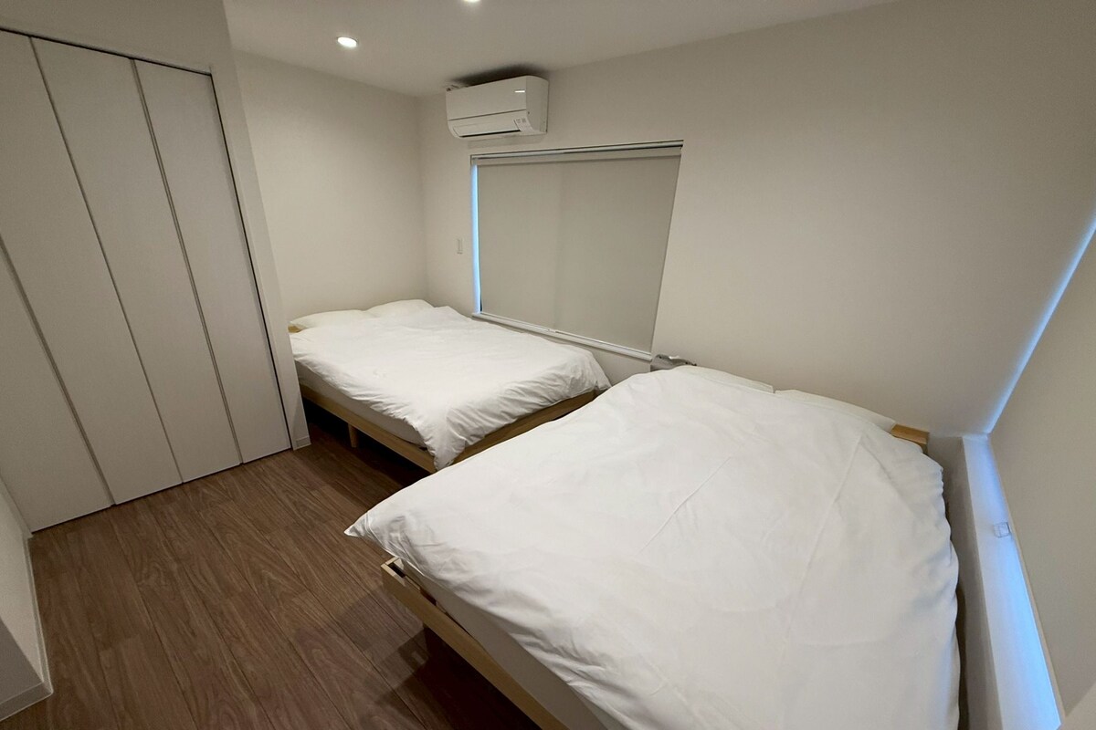 Ein kleines Hotelzimmer mit zwei Einzelbetten, einem Kleiderschrank und einer Klimaanlage.