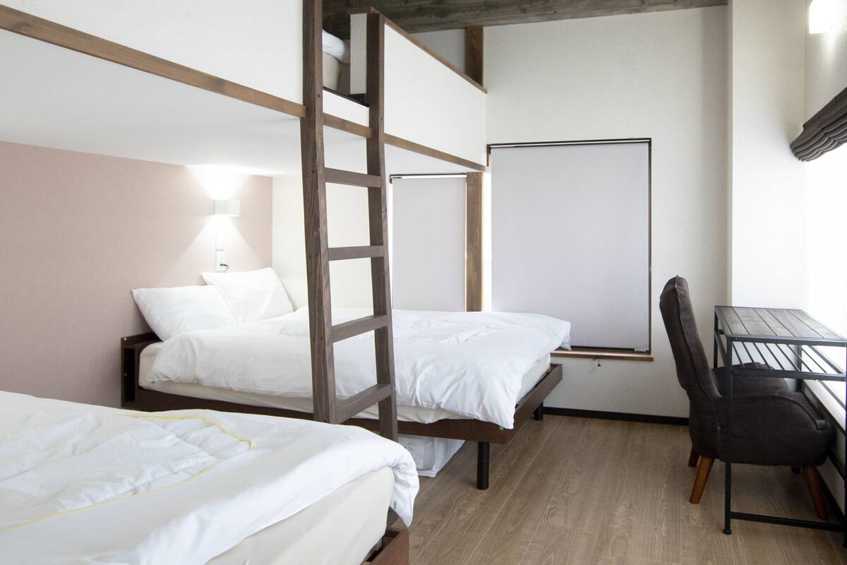 A room with bunk beds, a desk, and a chair.