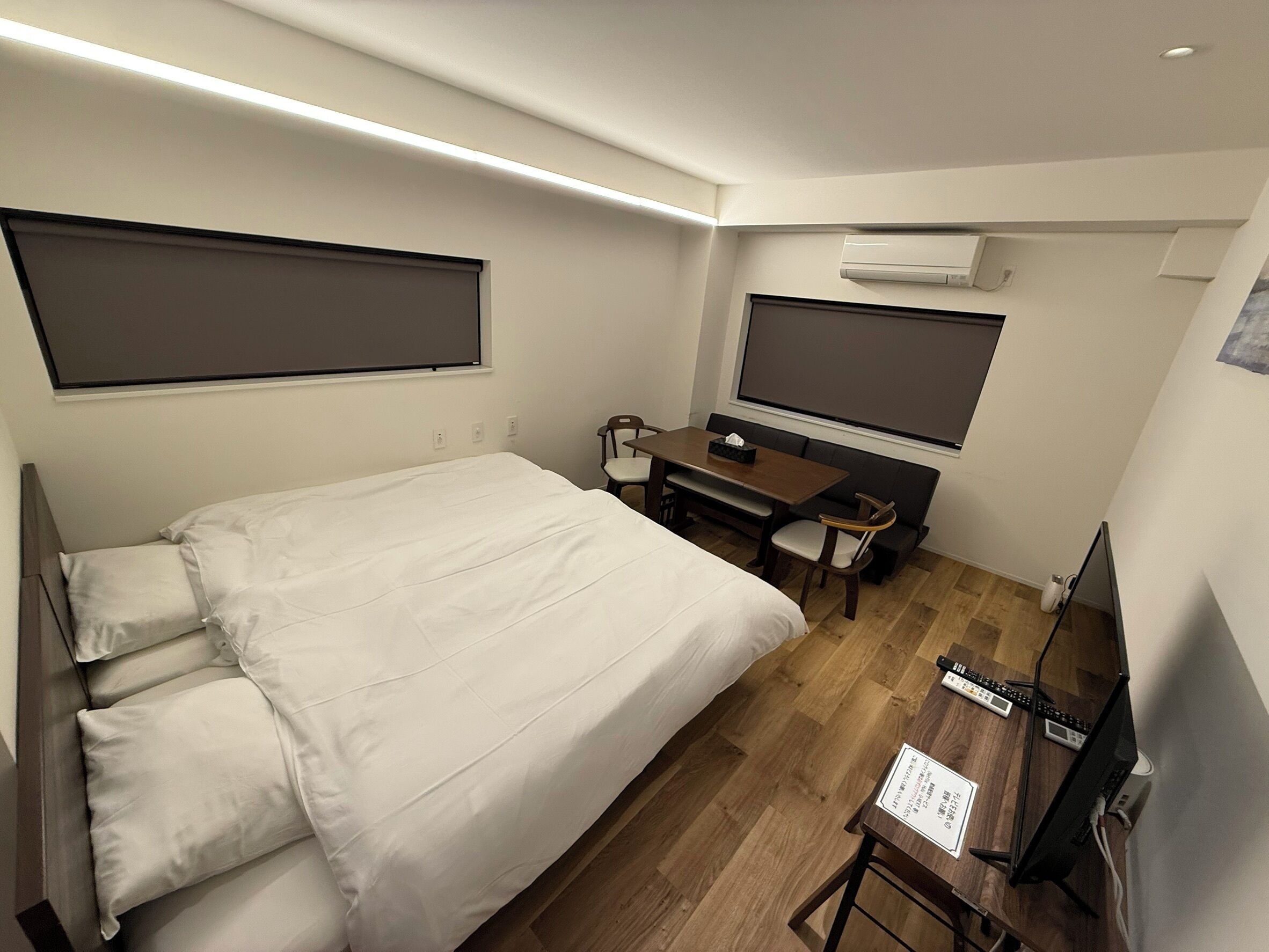 Habitación de hotel con cama, escritorio, computadora, televisor y aire acondicionado.
