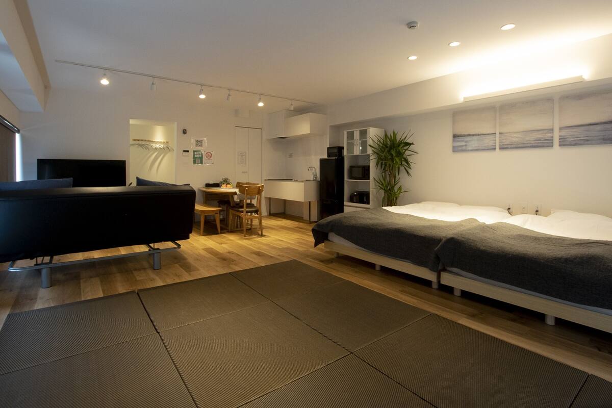 A modern hotel room with a bed, a desk, a chair, a television, and a plant.