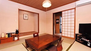 A traditional Japanese-style room with tatami flooring, a wooden table, and a television. - Mitaniya (Ito)