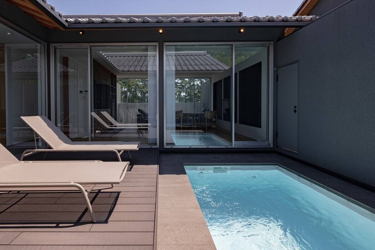 Ein moderner Poolbereich im Freien mit Liegestühlen und einer glasvergrößerten Terrasse.