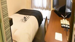 Une chambre d’hôtel avec un lit, un bureau avec une télévision et une fenêtre avec des rideaux.