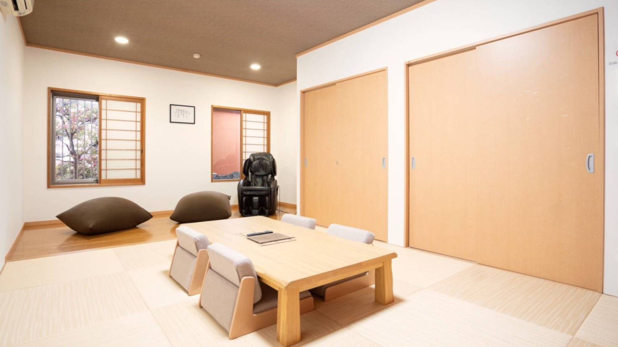 Una habitación con una mesa de madera, sillas, una bolsa negra y una puerta grande.