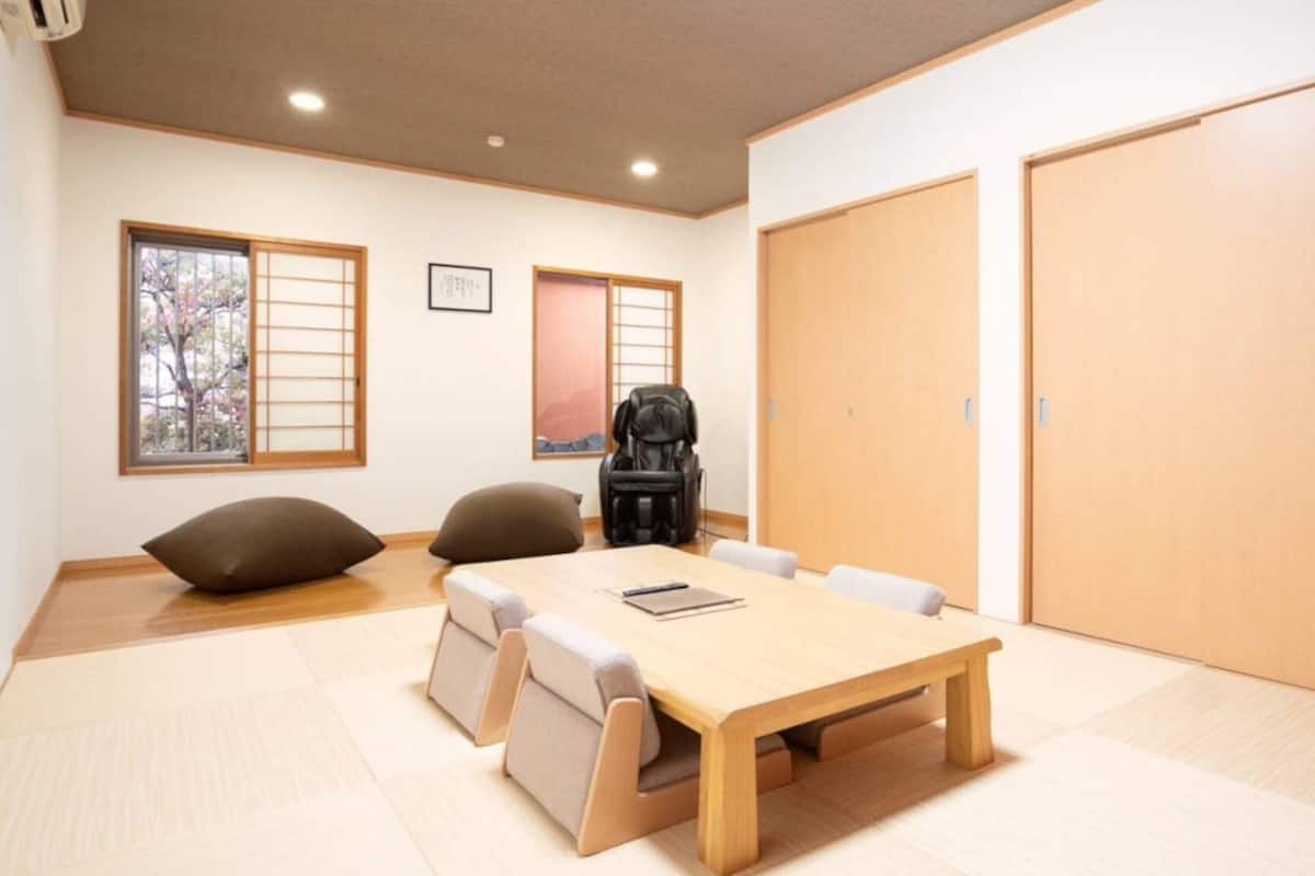 Ein Zimmer mit einem Holztisch, Stühlen, einer schwarzen Tasche und einer großen Tür.