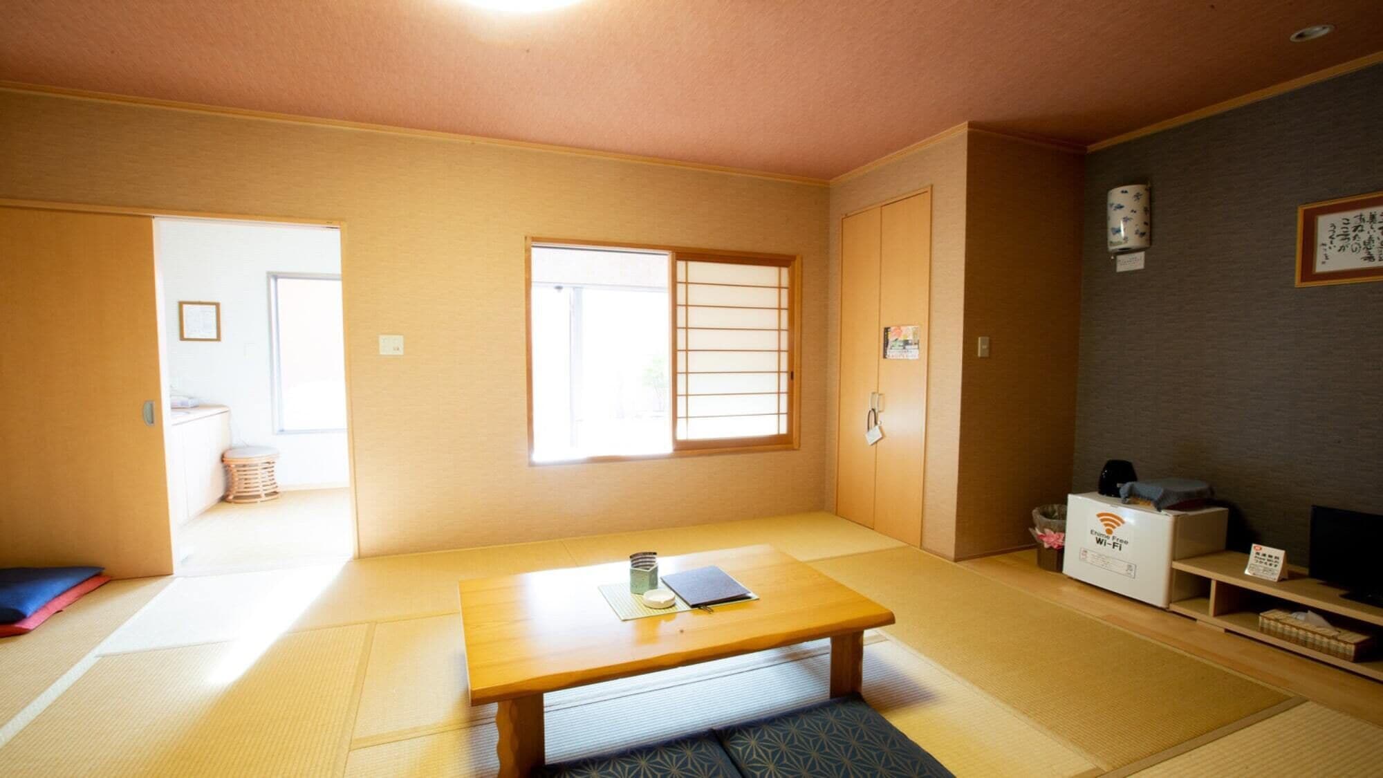 A traditional Japanese room with tatami flooring, a low wooden table, a sliding door, and a television on a stand.