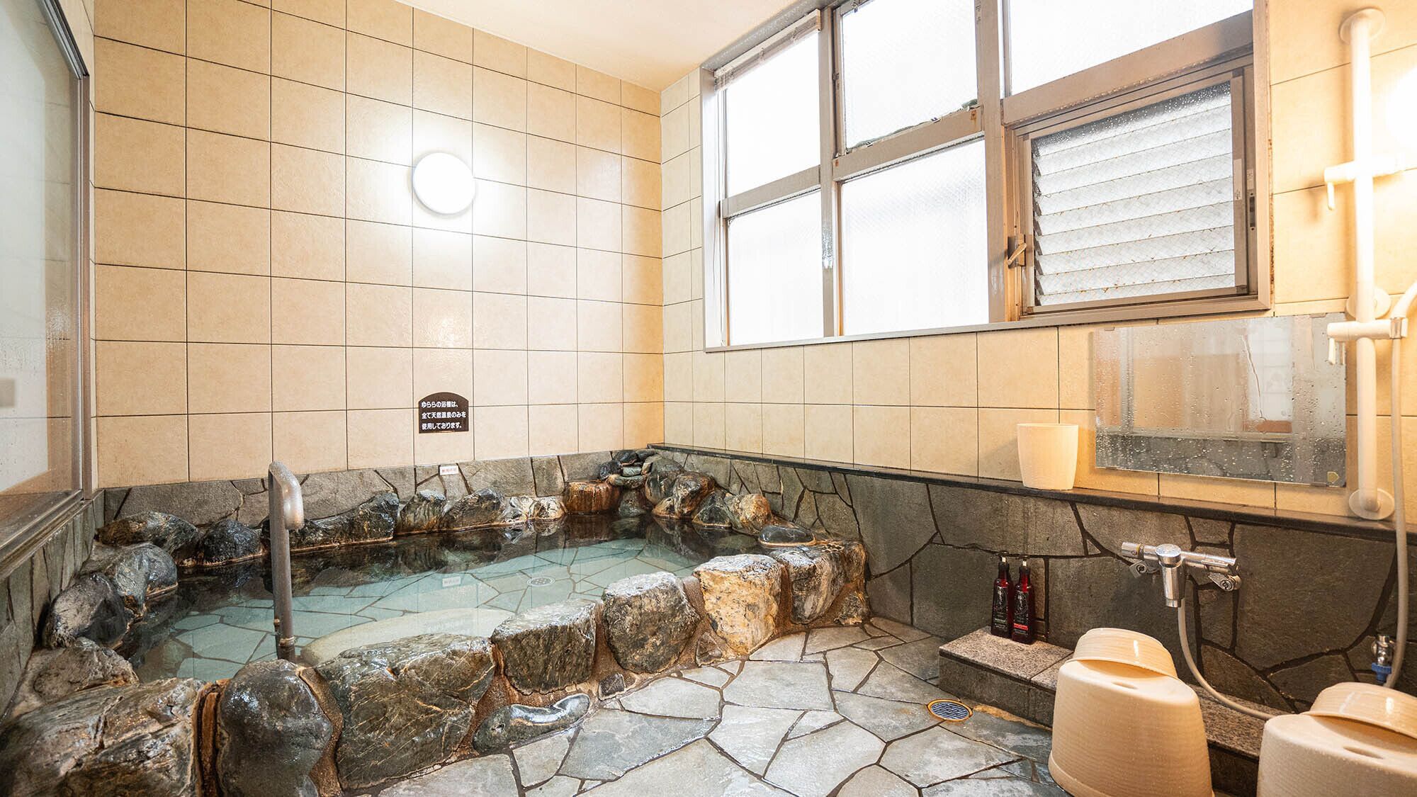 Un baño con una bañera de piedra, una ventana y un cartel en la pared.