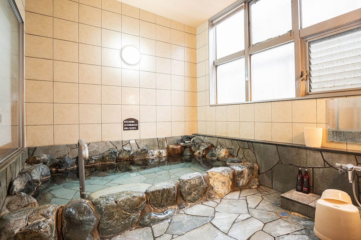 Ein Badezimmer mit einer Steinbadewanne, einem Fenster und einem Schild an der Wand.