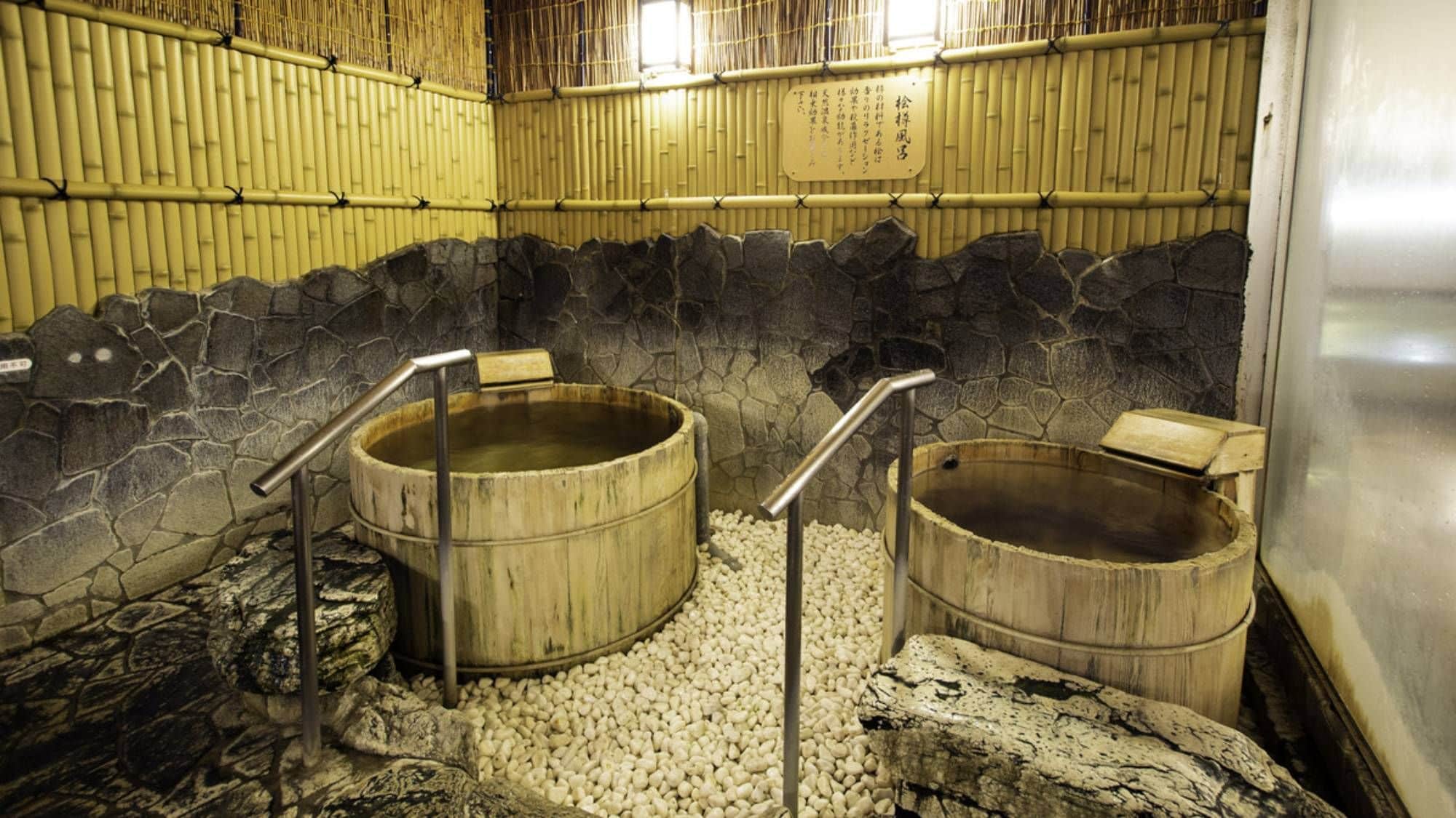 Un área de baño tradicional con paredes de piedra y tinas de madera.