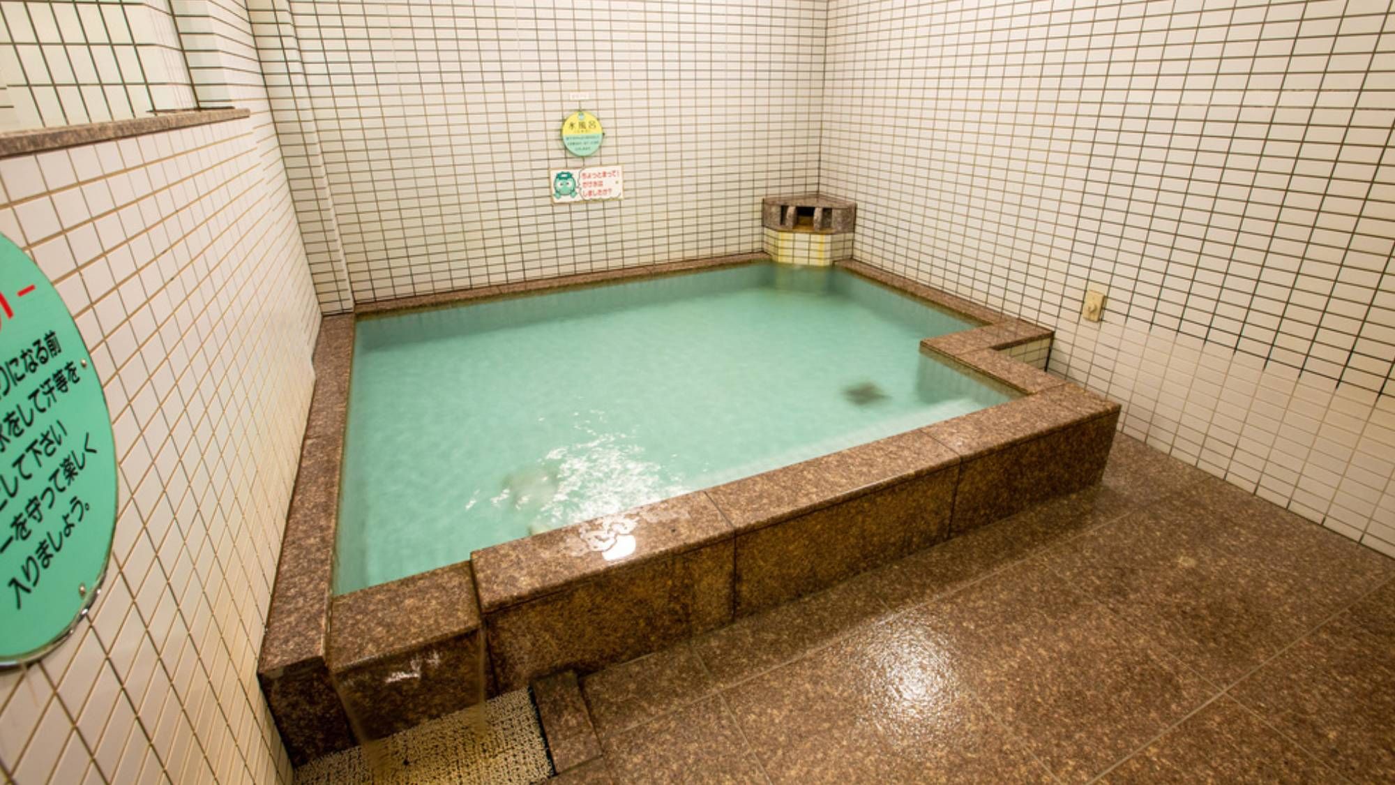 Un jacuzzi pequeño y rectangular con interior de azulejos y un cartel en la pared.