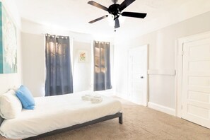 A bedroom with a bed, a ceiling fan, and a door. - Heart of Downtown, Shops & Dining - Cozy Craftsman (Columbus)
