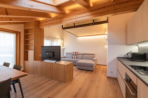 Ein kompakter Wohnbereich mit Essbereich, einer Couch, einem Fernseher und einer Küchenzeile.