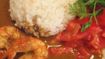 A plate with white rice, shrimp, and a tomato-based sauce, garnished with parsley.