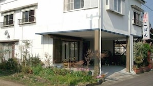 Un edificio de dos pisos con un porche cubierto, una antena parabólica y un letrero con caracteres japoneses.