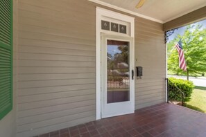 Una casa con una porta bianca, un piccolo portico e una bandiera americana.