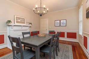 A dining room with a rectangular table, six chairs, a chandelier, a fireplace, and decorative wall art. - Historic Parkside Home w/ Fenced Yard, (Columbus)