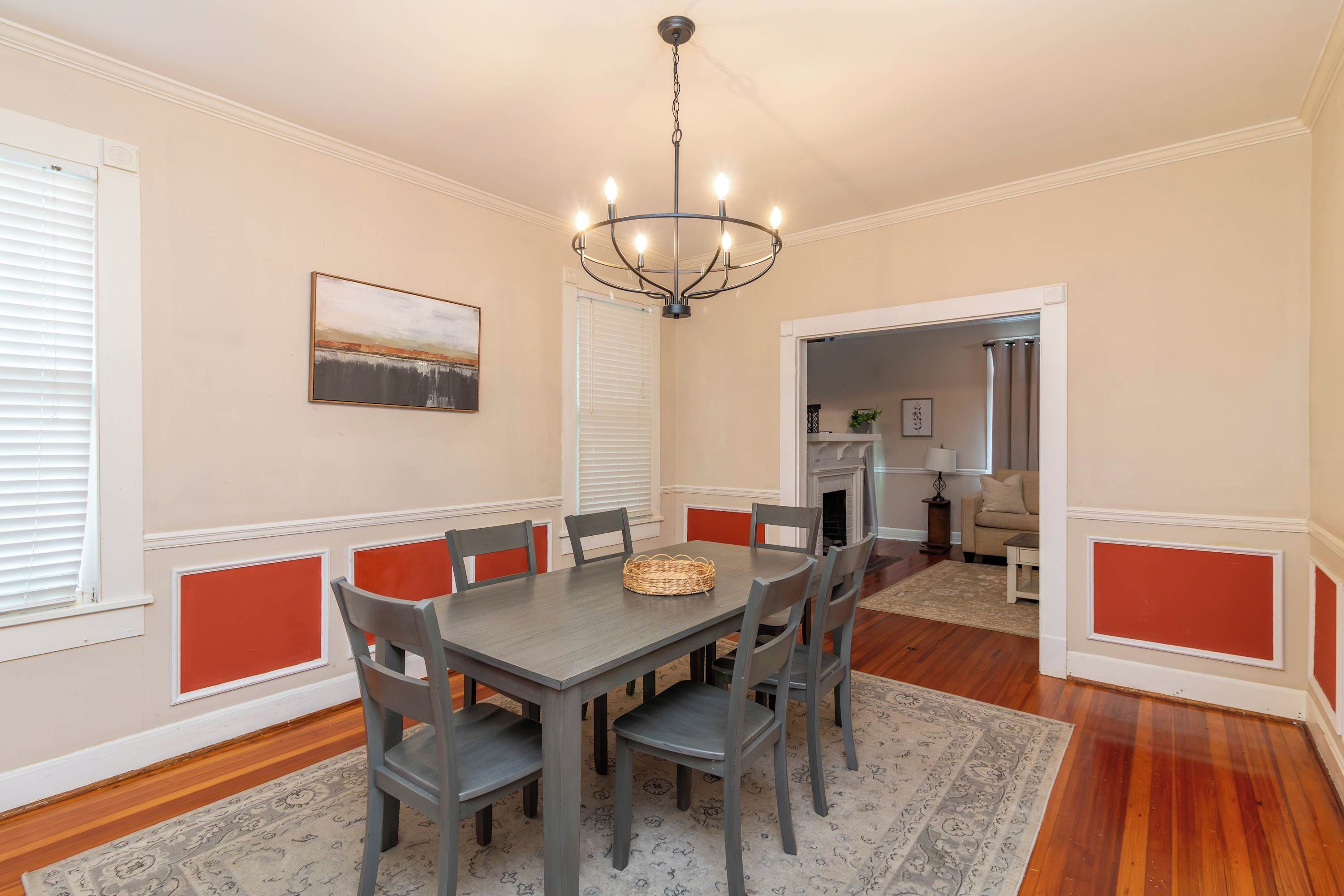 Une salle à manger avec une table, des chaises, un lustre et un tableau au mur.