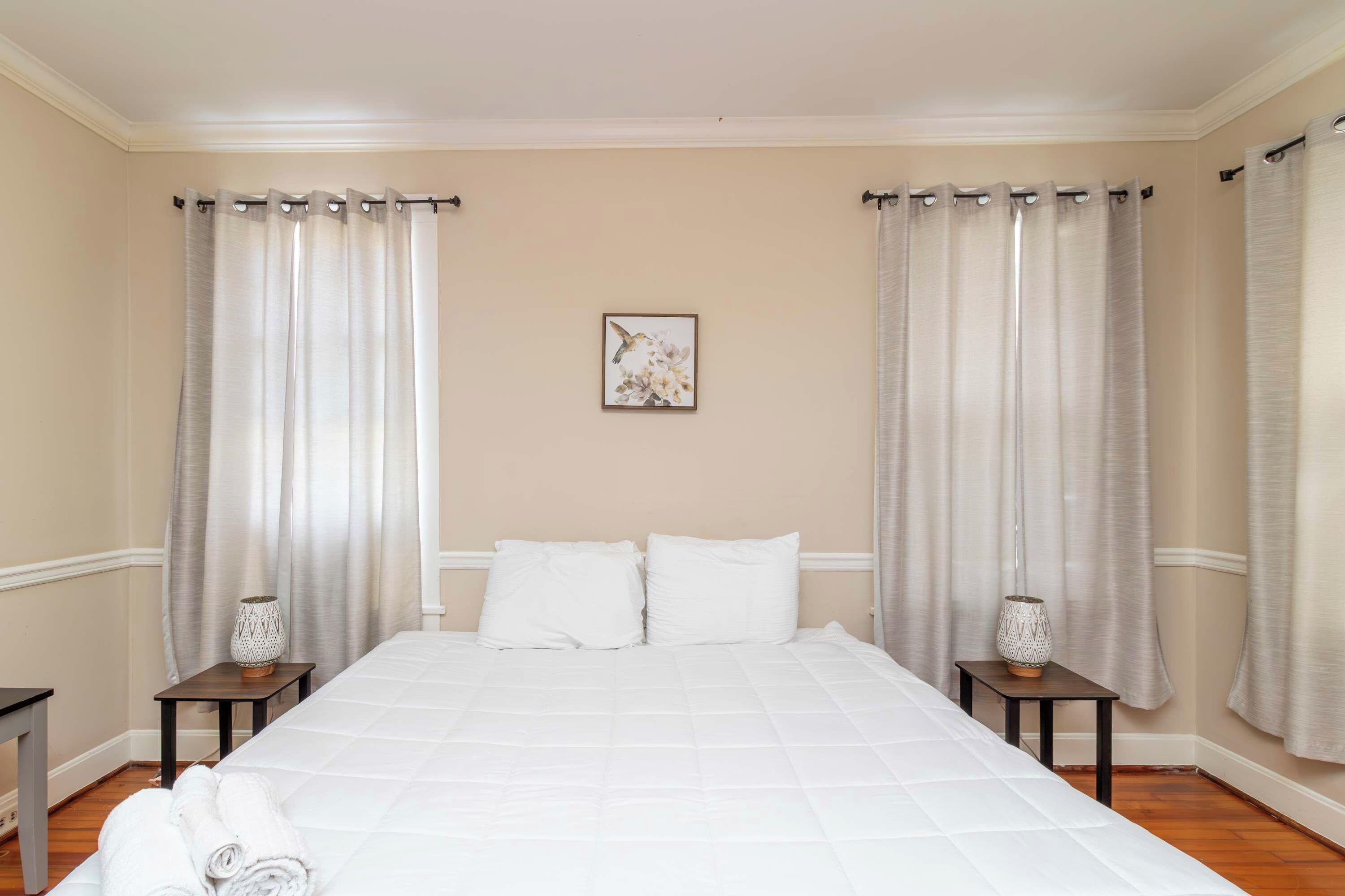 Une chambre d’hôtel avec un grand lit, deux tables de chevet avec des lampes et un tableau au mur.
