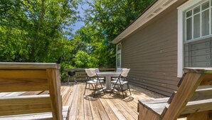 Une terrasse en bois avec une table et des chaises, entourée d’arbres.