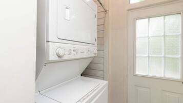 A white front-loading washer and dryer unit with a control panel, installed against a wall with a window above.