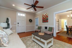 A living room with a ceiling fan, a sofa, a coffee table, and a painting on the wall. - Historic Parkside Home w/ Fenced Yard, (Columbus)