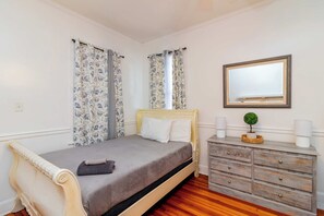 A bedroom with a bed, a dresser, a mirror, and a small potted plant. - Historic Parkside Home w/ Fenced Yard, (Columbus)