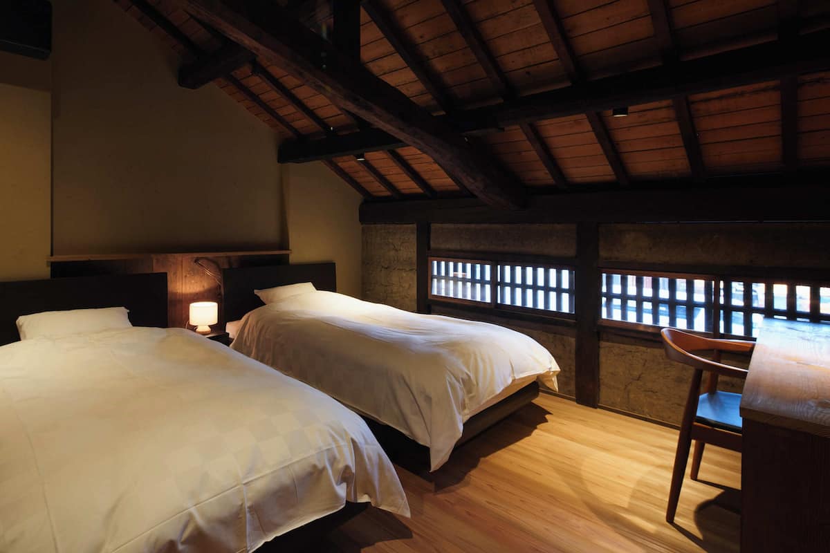 A room with two beds, a desk, and a chair.