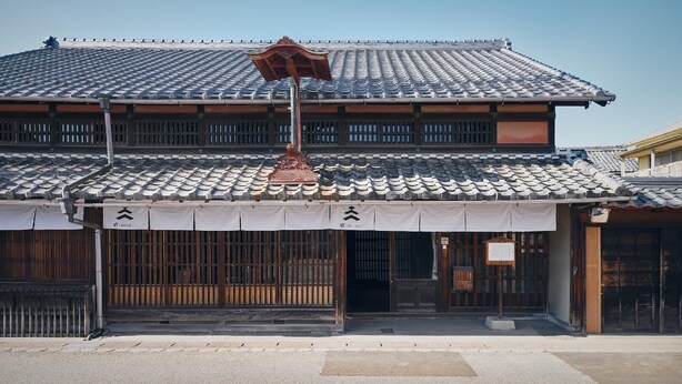 A traditional Japanese building with a tiled roof, wooden lattice windows, and a covered entrance. - Shuku (Inuyama)
