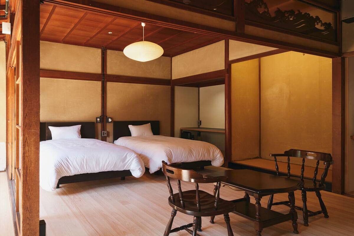 A traditional Japanese-style room with two beds, a wooden table, and a chair.