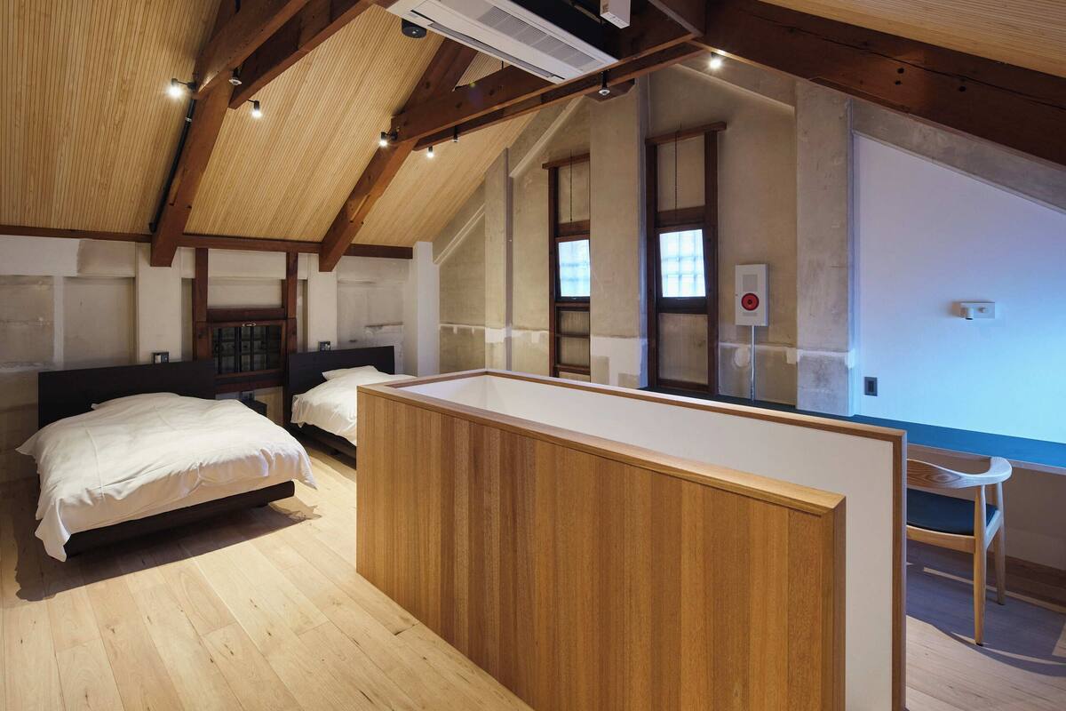 A bedroom with a wooden bed, a small wooden desk, and a window.