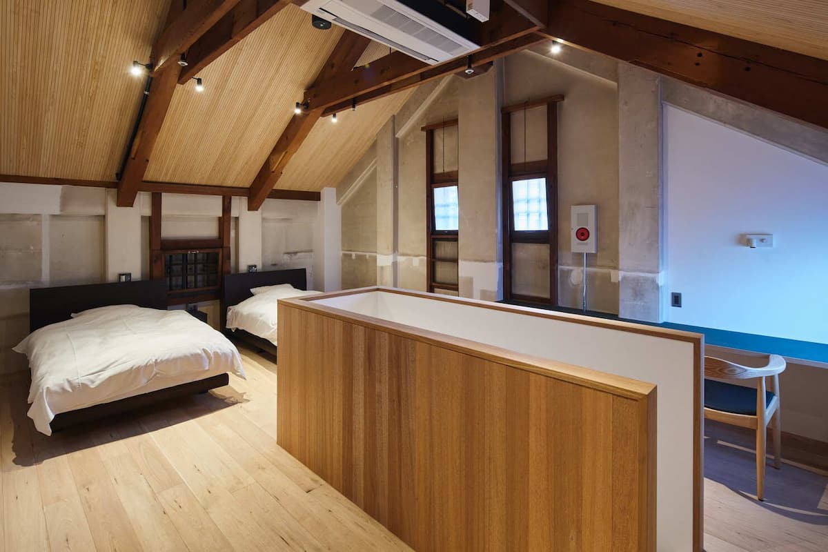 A bedroom with a wooden ceiling, a bed, a desk, and a chair.