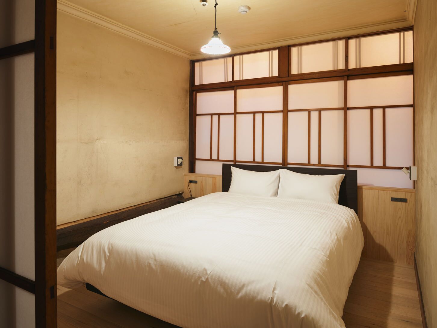 Une chambre à coucher avec un lit, une tête de lit en bois et une fenêtre donnant sur un beau paysage.