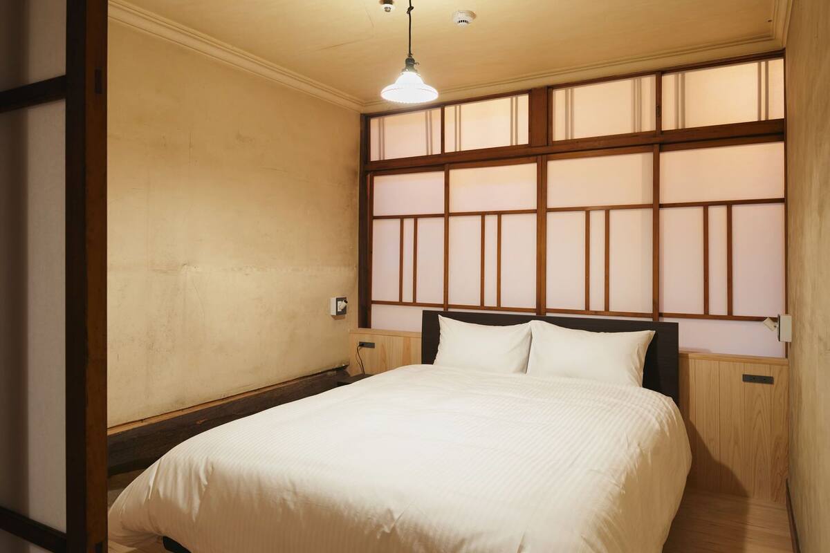A bedroom with a bed, wooden headboard, and a window with a view.