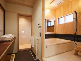 A bathroom with a bathtub, a towel rack, a wooden cabinet, and a window.