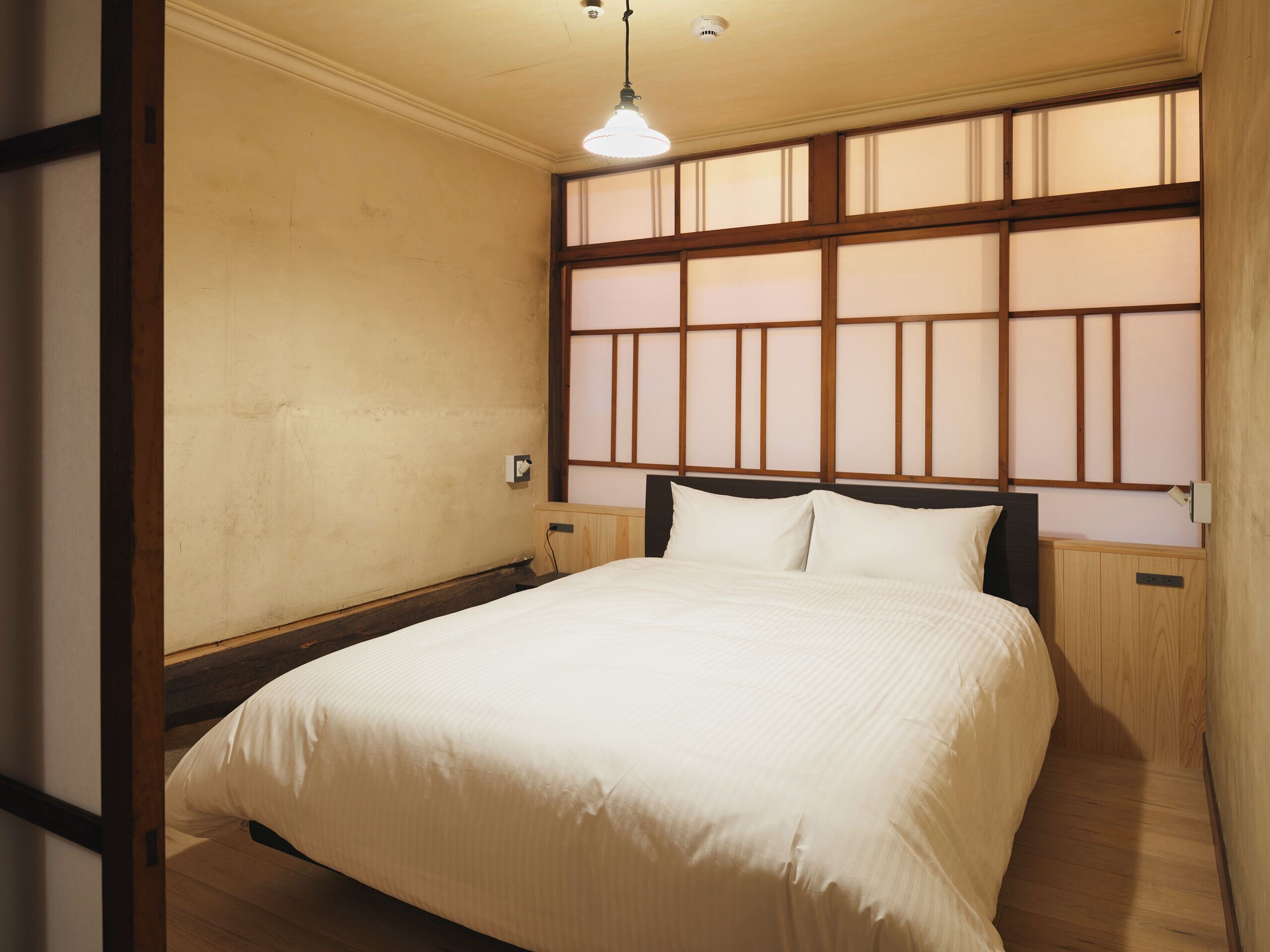 Une chambre à coucher avec un lit, une tête de lit en bois et une fenêtre donnant sur un beau paysage.