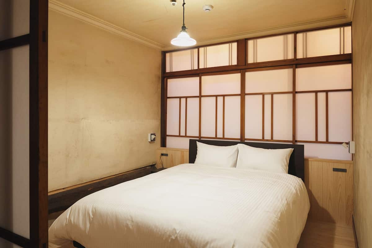 A bedroom with a bed, wooden headboard, and a window with a view.