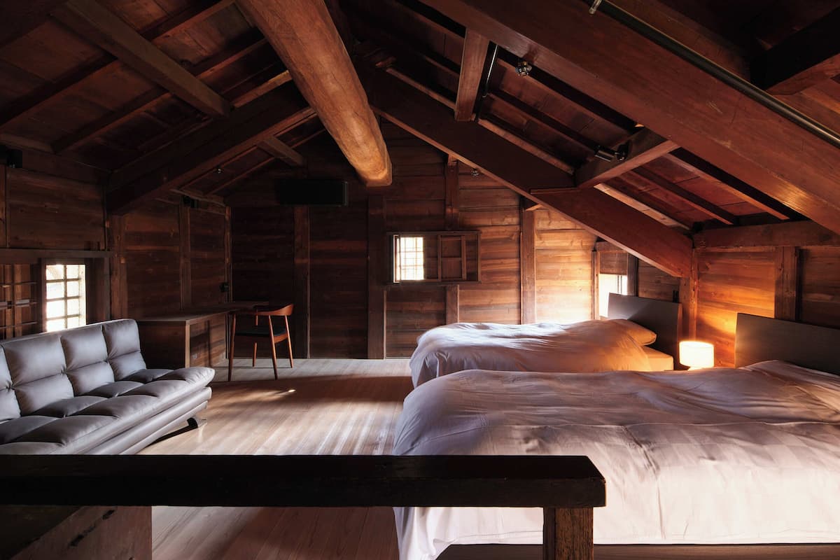 A log cabin interior with a sofa, a bed, and a desk.