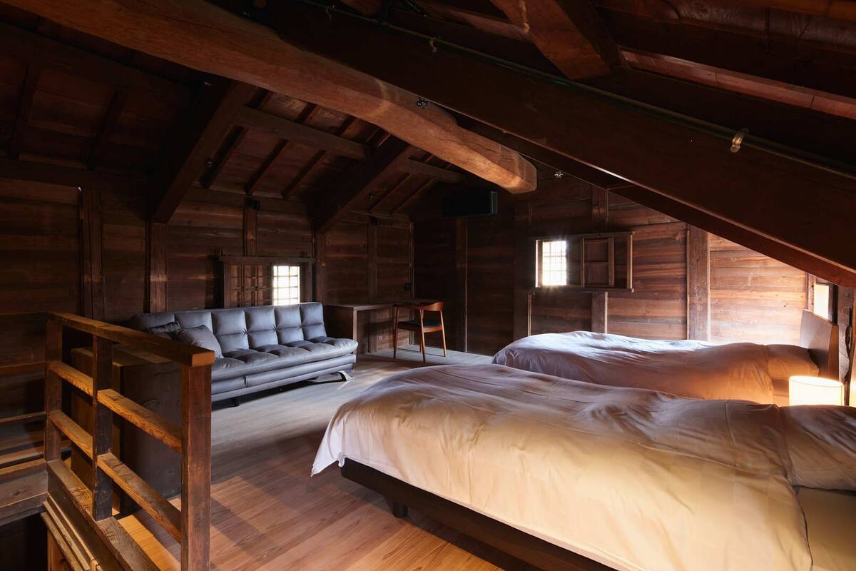 A log cabin interior with a loft bed, a sofa, and a desk.