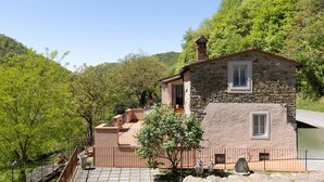 Un bâtiment en pierre doté d’un balcon, entouré d’arbres et surplombant un ciel dégagé.